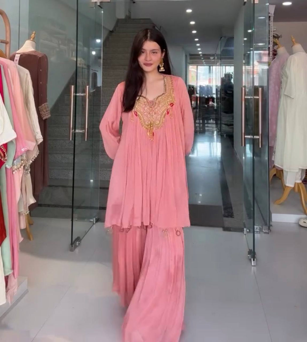 Woman in a pink traditional outfit standing in a clothing store.