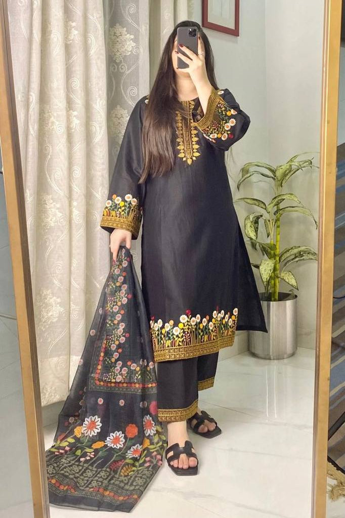 Person wearing a black traditional outfit with floral patterns in a room.